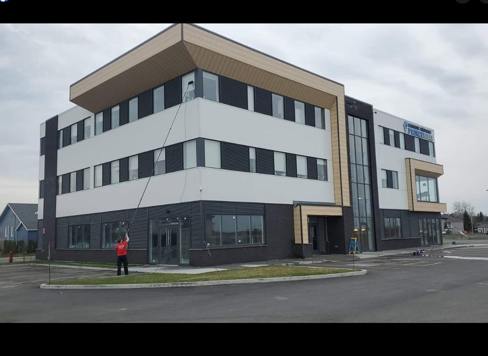 Technicien OMAX lavant la façade vitrée d'un édifice commercial à la perche à eau pure