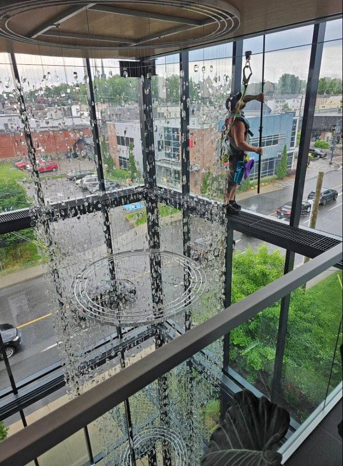 Technicien OMAX en suspension, harnais de sécurité, lavage de vitres en hauteur