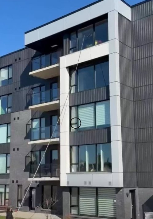 Technicien OMAX lavant les vitres d'un condo à étages avec une perche télescopique